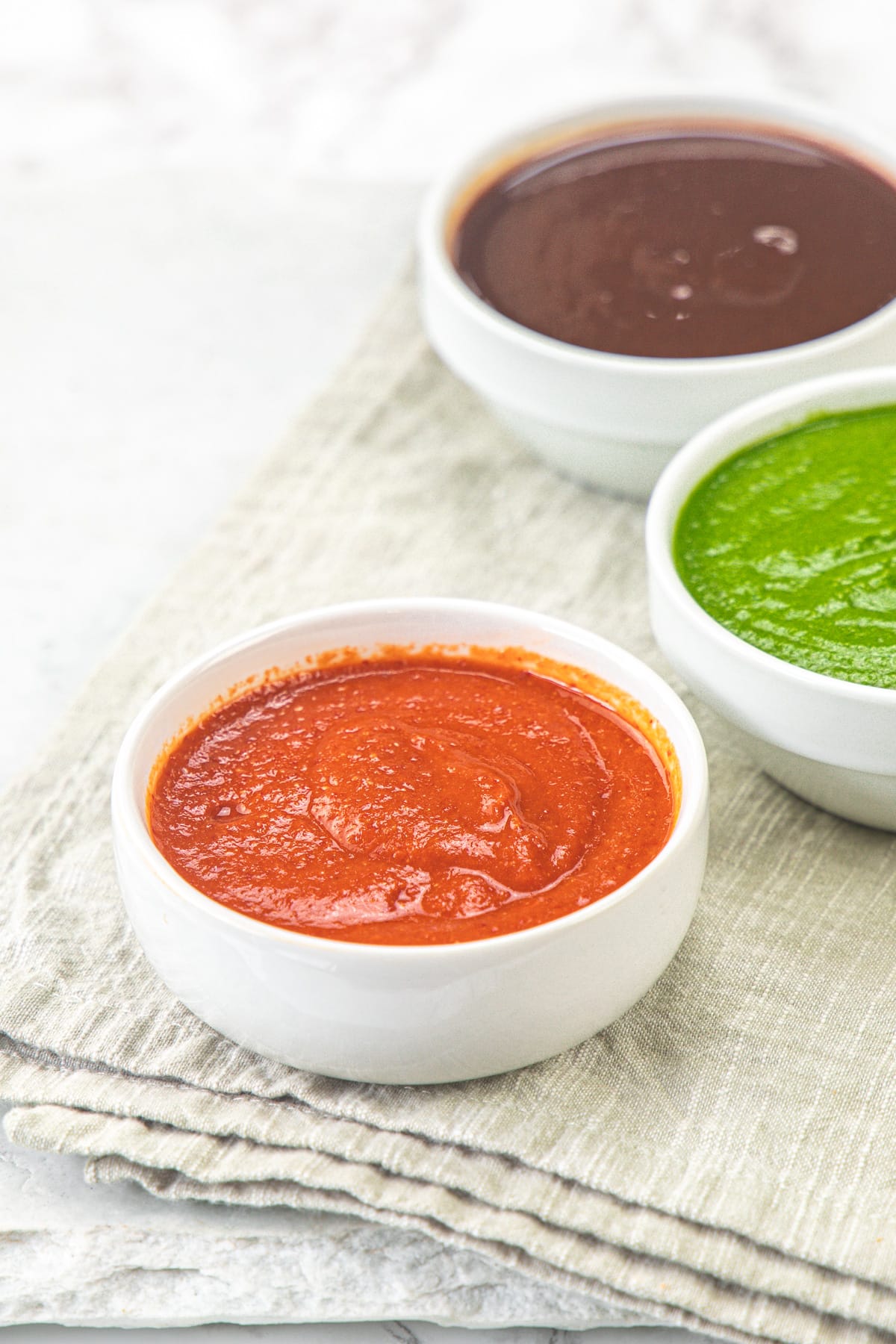 Garlic chutney bowl with green chutney and meethi chutney bowls in the back.