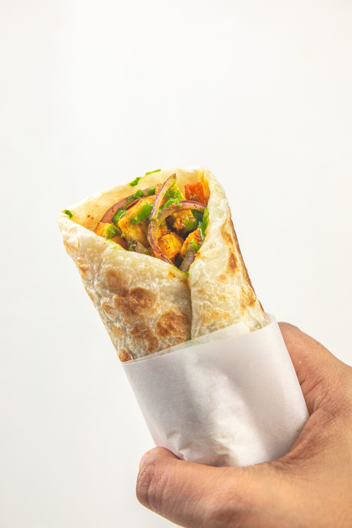 Holding one paneer wrap aka paneer kathi roll in a hand.