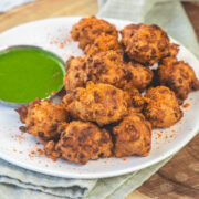 Corn pakoda with a sprinkle of dry garlic chutney served with green chutney.