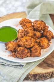 Corn pakoda with a sprinkle of dry garlic chutney served with green chutney.