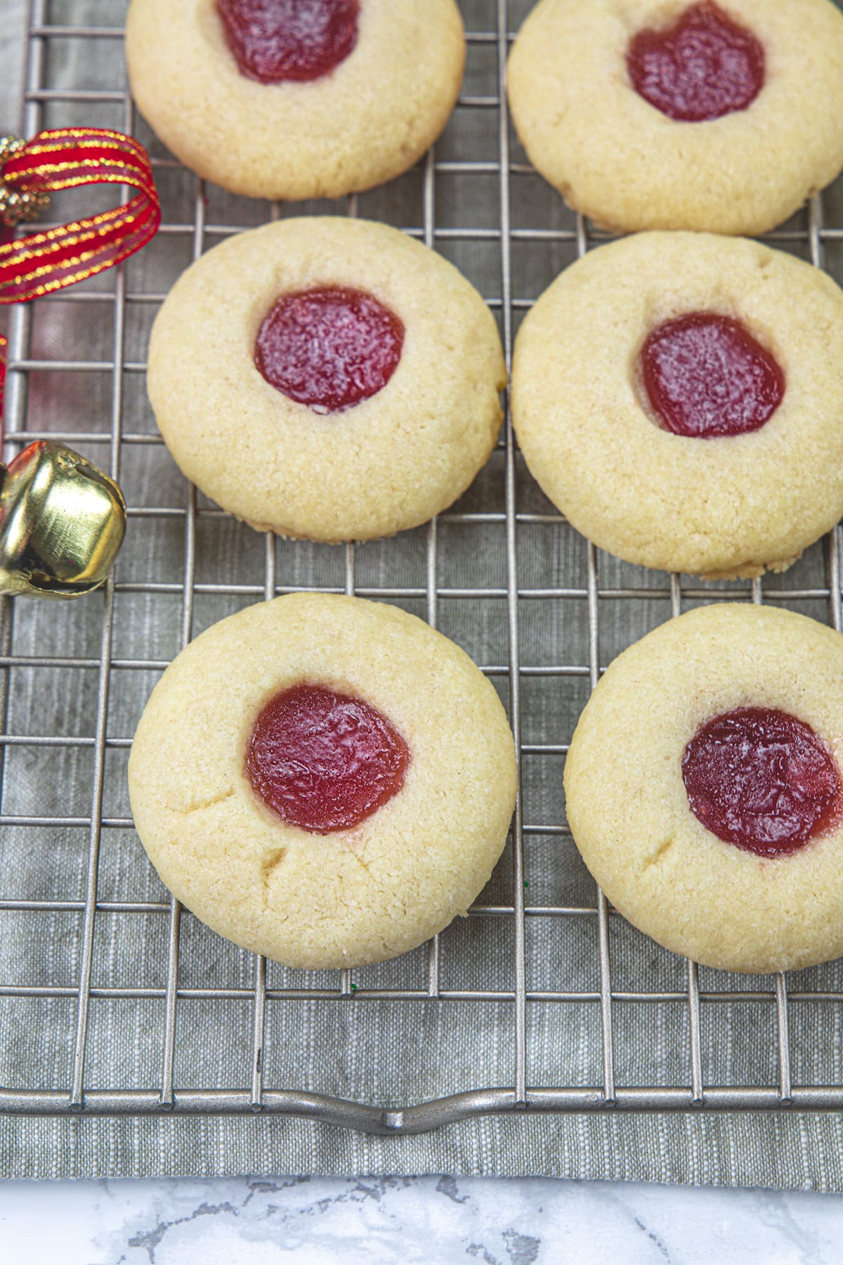 Eggless thumbprint cookies on a cooling rack with napkin under the rack.