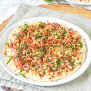 Masala papad in a plate with napkin and wooden board under it.