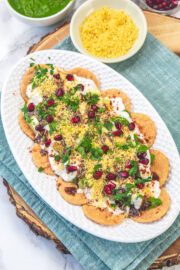 A plate of papdi chaat with napkin under the plate and a bowl of sev on the side.