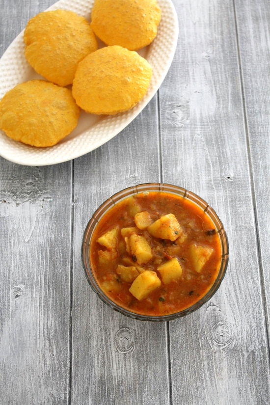 Aloo tamatar ki sabzi in a bowl served with masala puri.