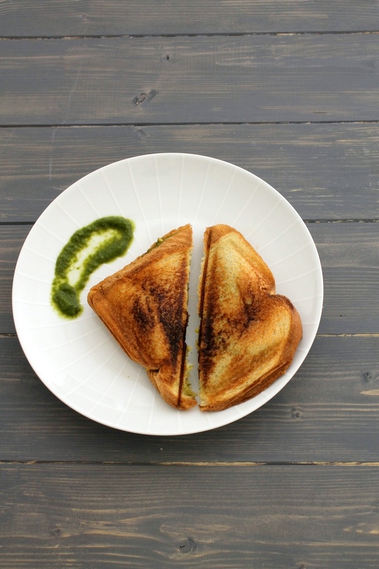 Corn sandwich triangles in a plate with green chutney.