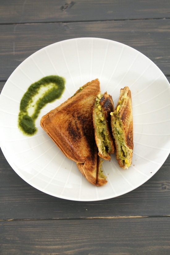 Corn sandwich cut into half served with cilantro chutney.