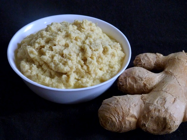 Ginger paste in a bowl with a piece of ginger on the side.