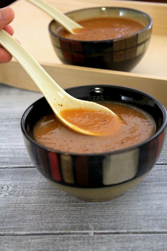 Taking a spoonful of mixed vegetable soup from the bowl.