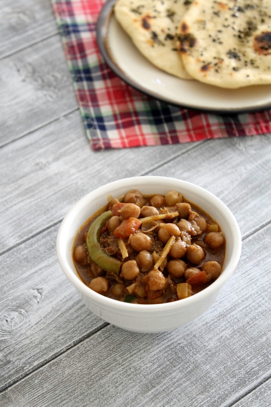 Amritsari Chole served in a white bowl with kulcha in the back.