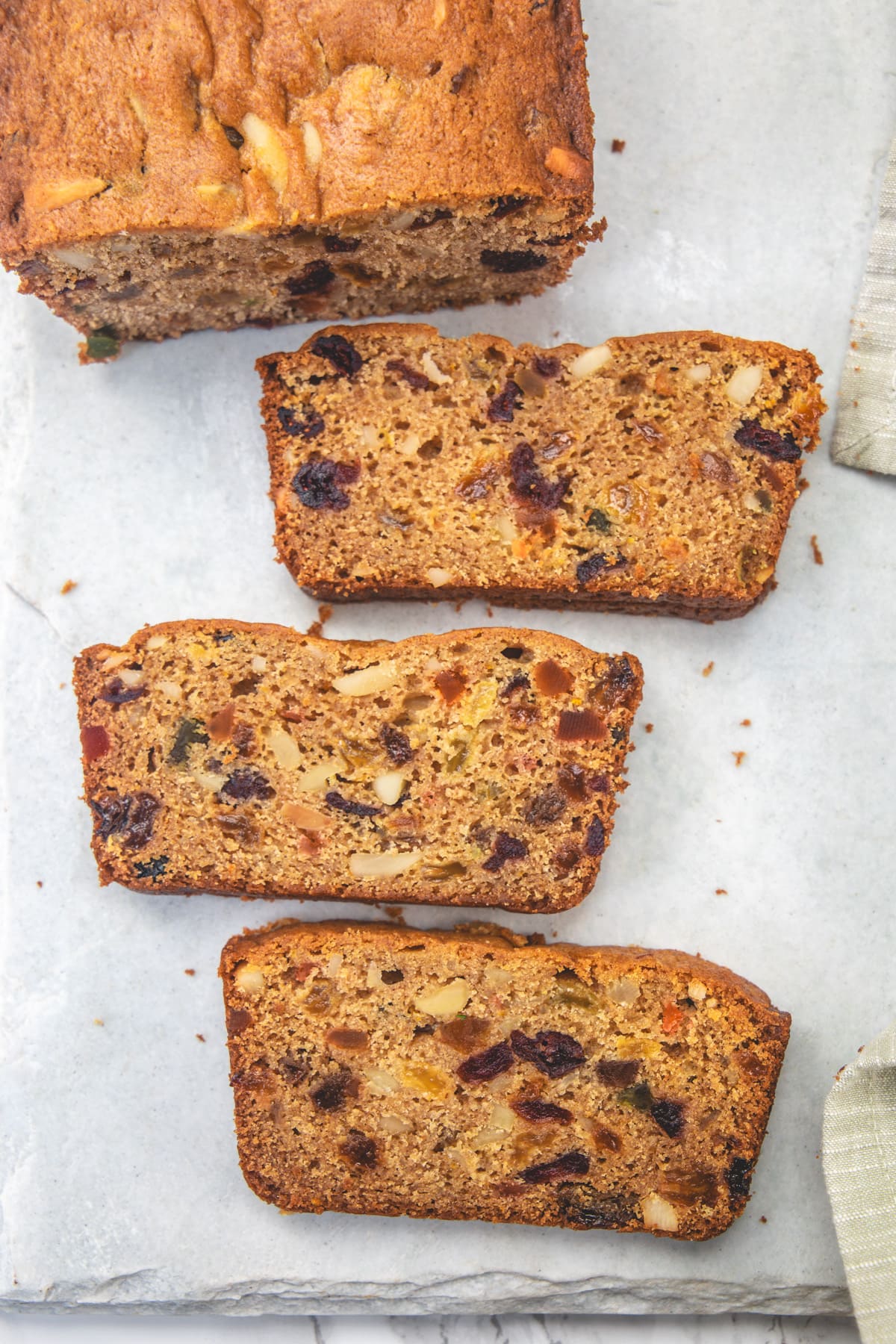 3 slices of eggless fruit cake on a marble board.