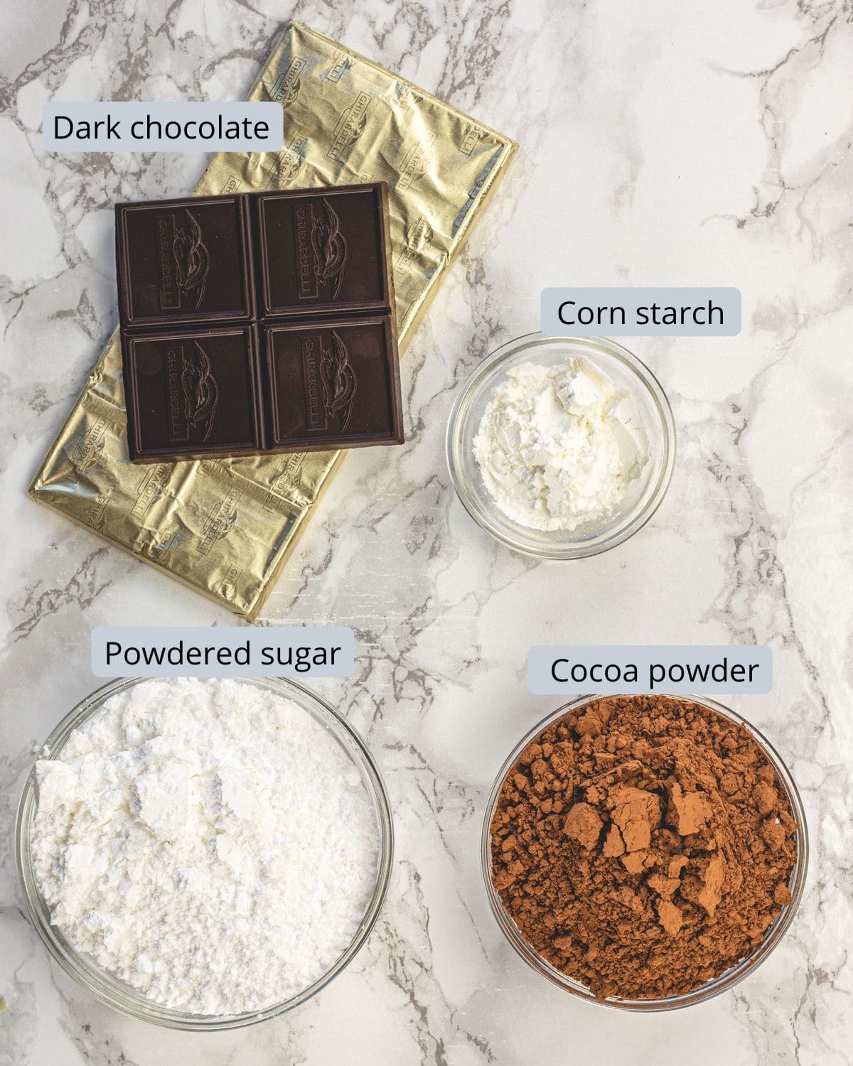 Hot chocolate mix ingredients in bowls with labels.