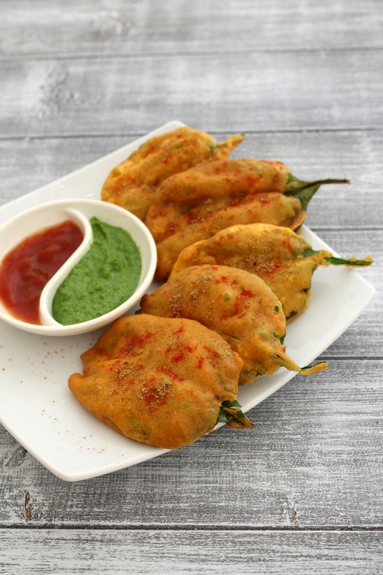 Palak pakora sprinkled with chaat masala and chili powder with a side of chutney and ketchup. 