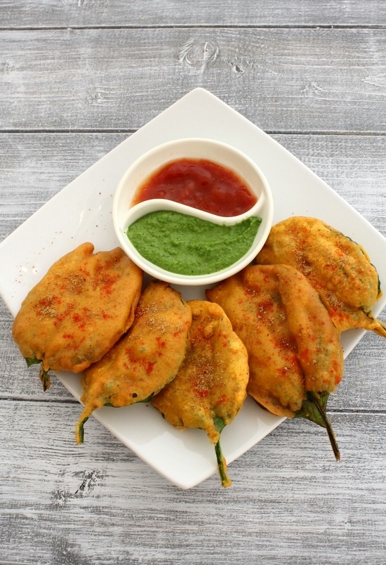 5 palak pakoda served in a plate with side of chutney and ketchup.