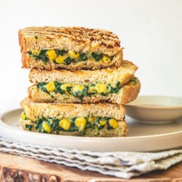 A stack of 3 Slices of spinach corn sandwich in a plate.