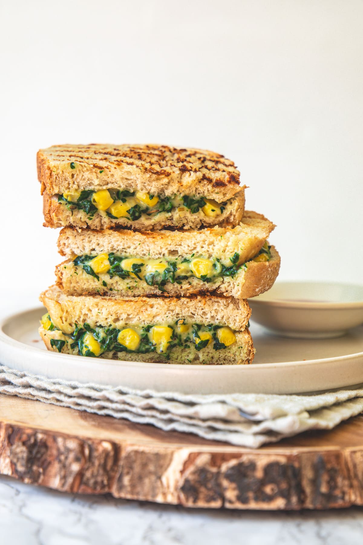 A stack of 3 Slices of spinach corn sandwich in a plate.