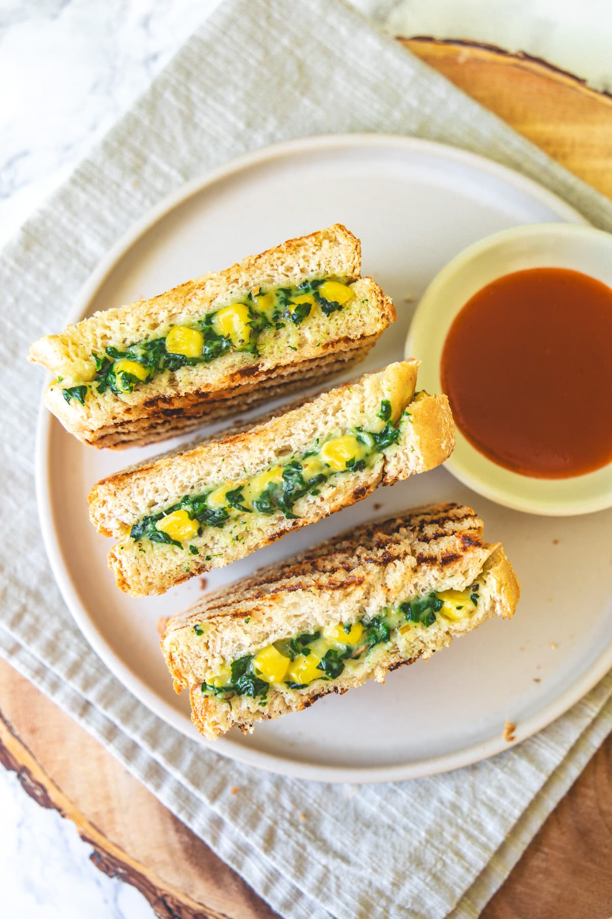 3 pieces of spinach corn sandwich with sweet chili sauce on the side.