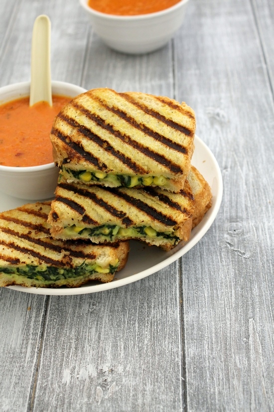 Spinach corn sandwich served in a plate with soup bowl on the side.