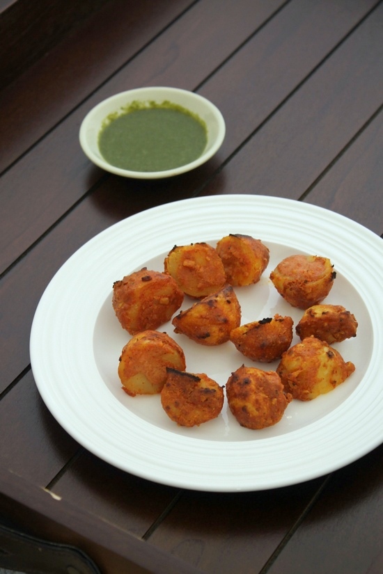 Tandoori Aloo served in a plate with green chutney on the side.