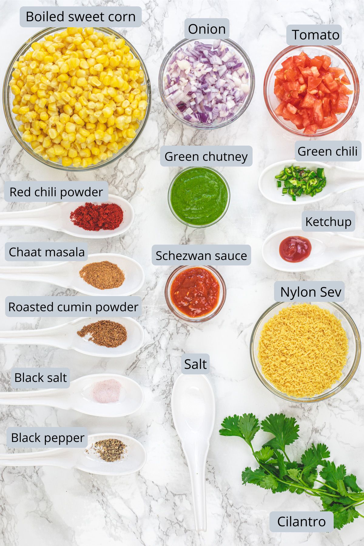 Corn chaat recipe ingredients in bowls and spoons with labels.