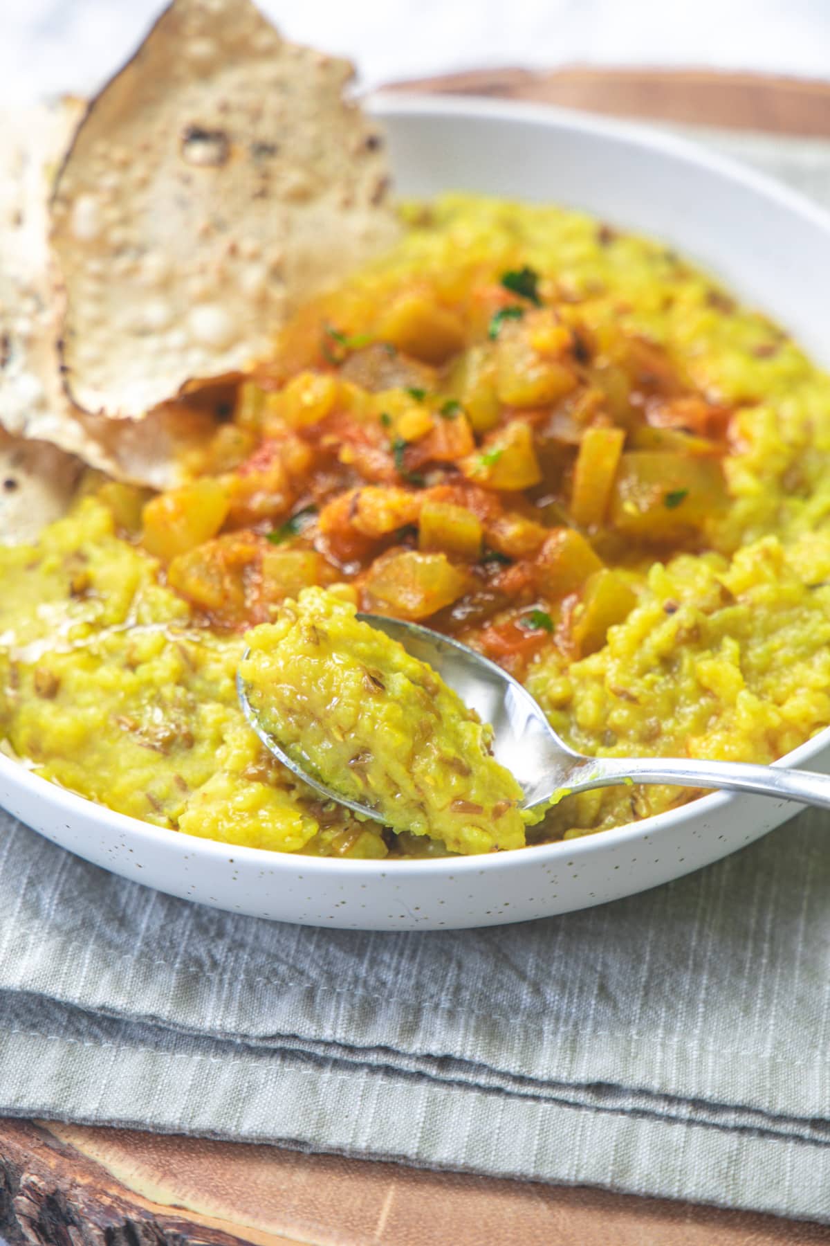 Taking a spoonful of khichdi from a khichdi shaak plate.