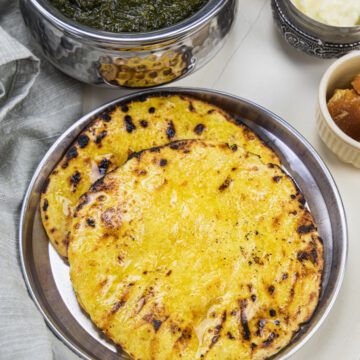 2 makki ki roti in a steel plate with saag.