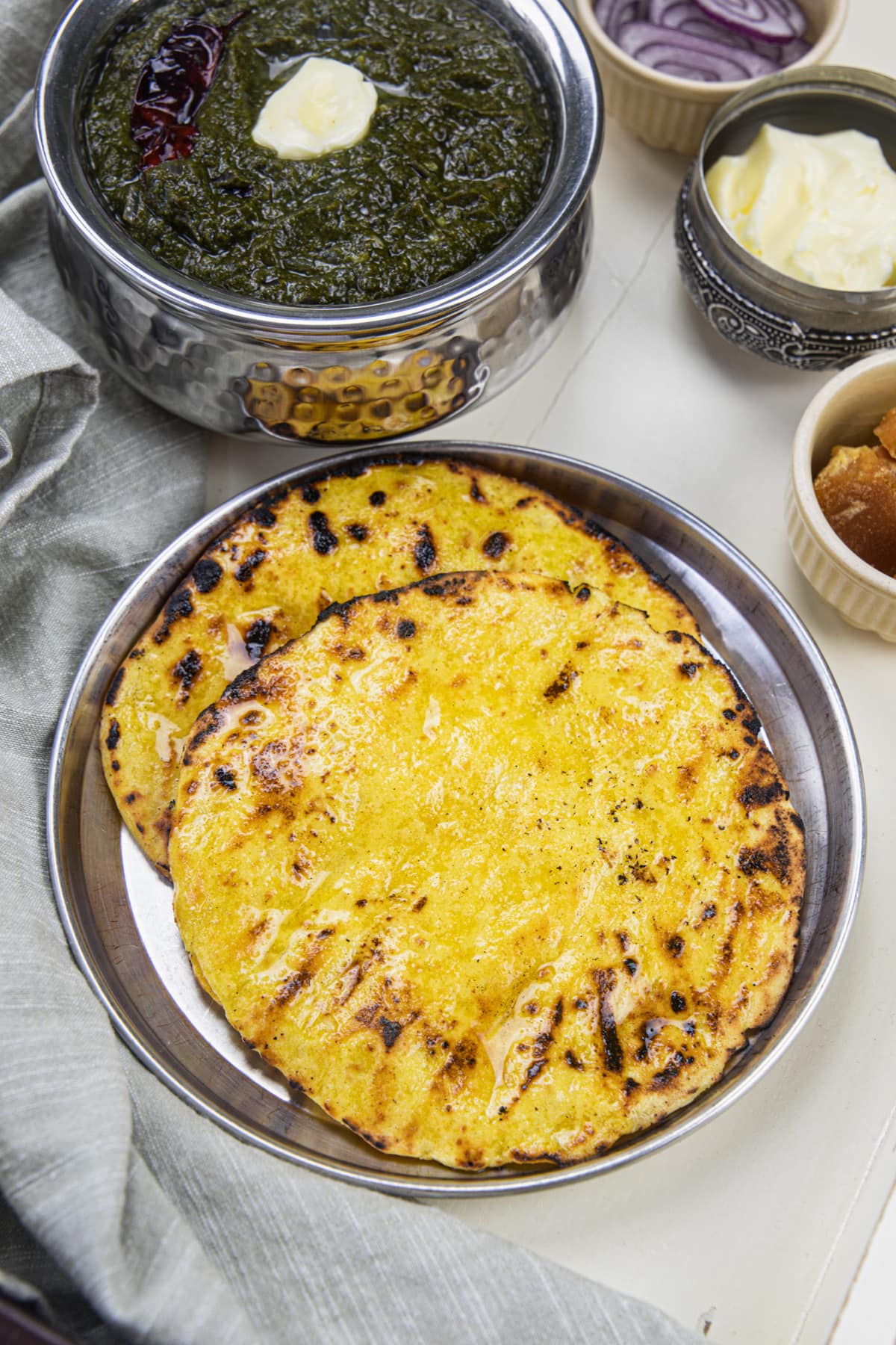 2 makki ki roti in a steel plate with saag.