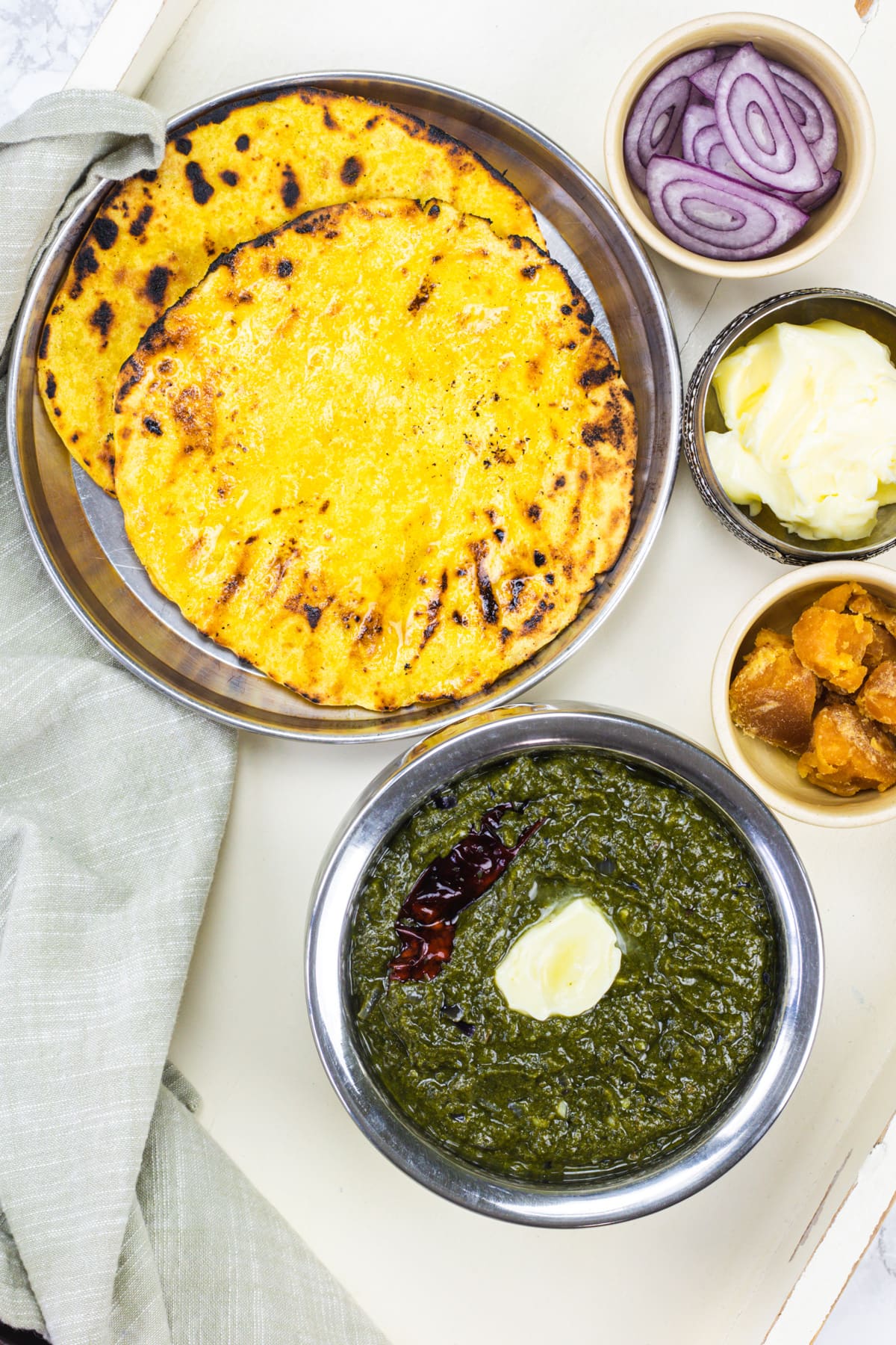 Sarson ka saag with makki ki roti and onion, jaggery and butter on the side.