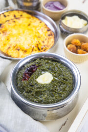 Sarson ka saag topped with butter and served with sides.