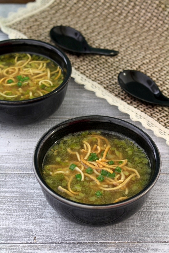 2 bowls of veg manchow soup topped with fried noodles with soup spoons on the side.