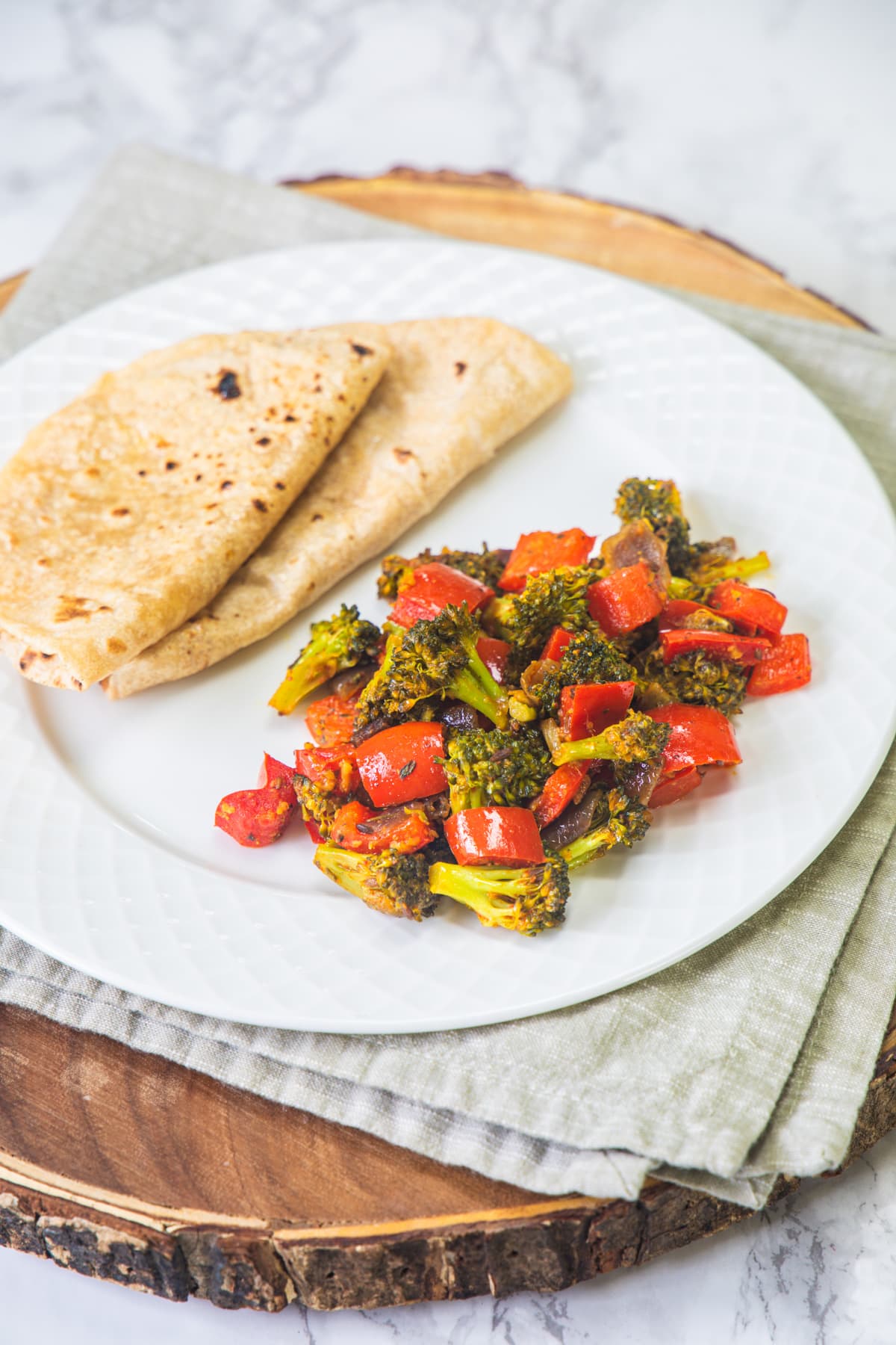 A plate with broccoli sabzi and 2 rotis.