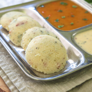 Rava idli in a plate with sambar and chutney.