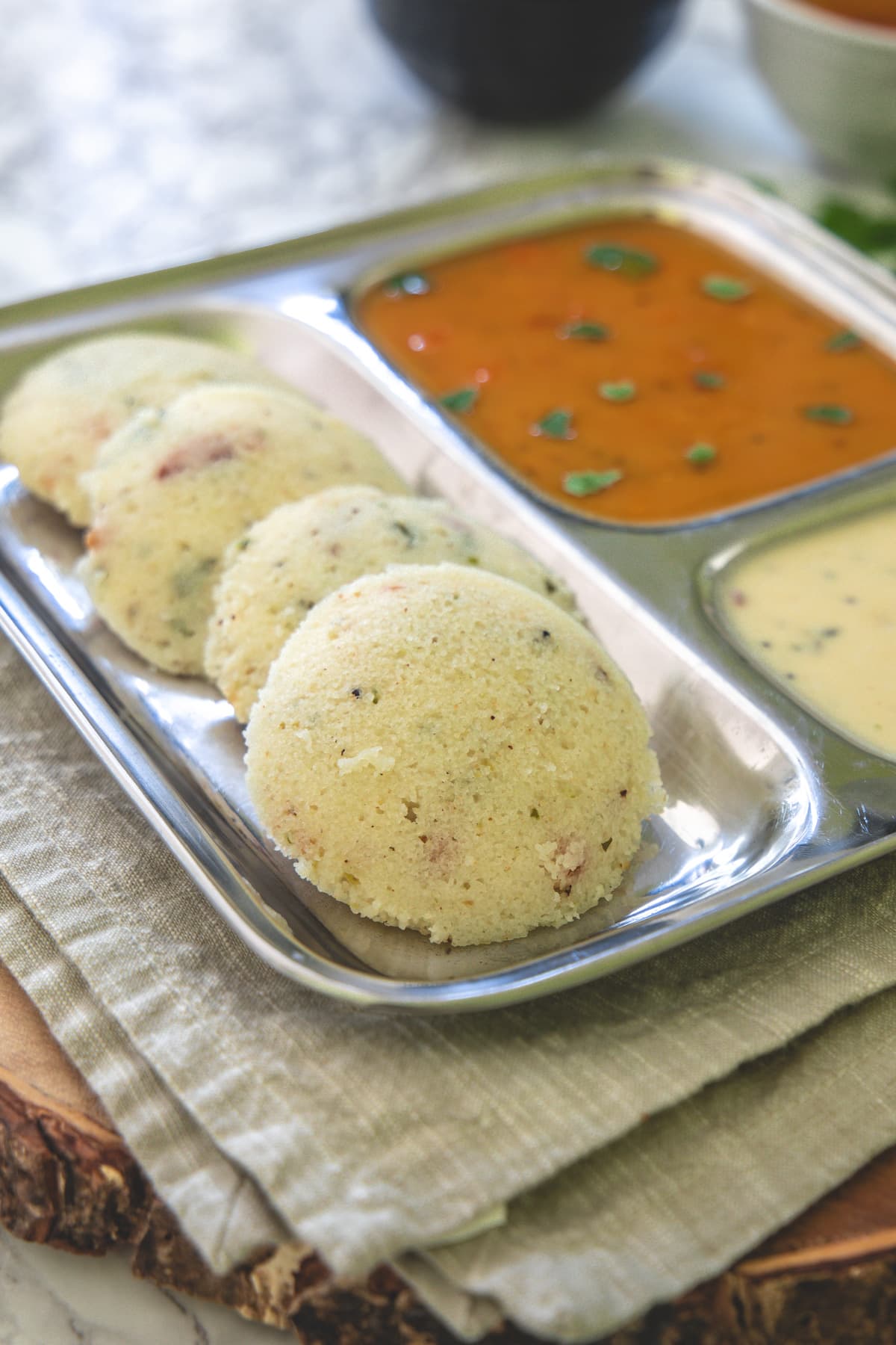 Rava idli in a plate with sambar and chutney.