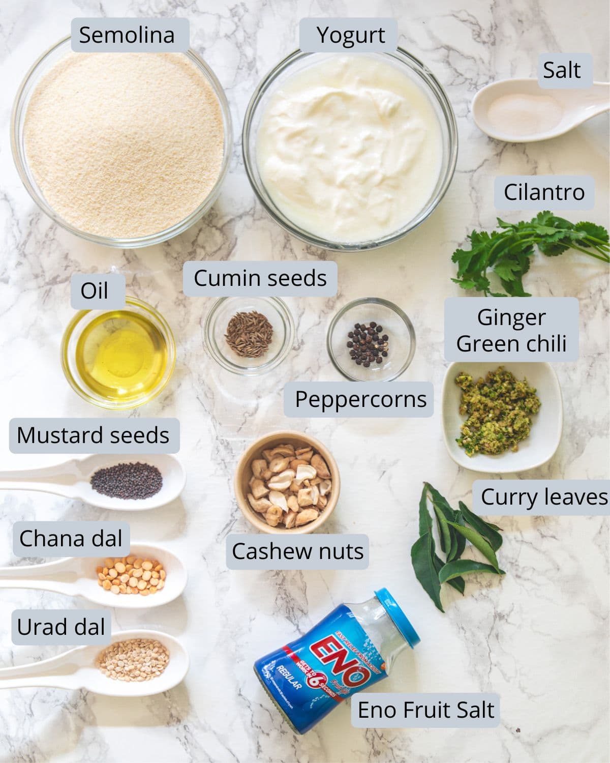 Rava idli ingredients in bowls and spoons with labels.