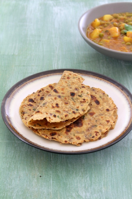 Onion paratha in a plate and first paratha folded in half.