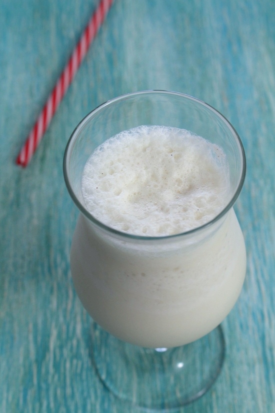 Vanilla milkshake glass with a straw on the side.