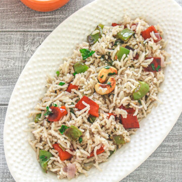 Capsicum pulao in an oval dish with bhindi raita.