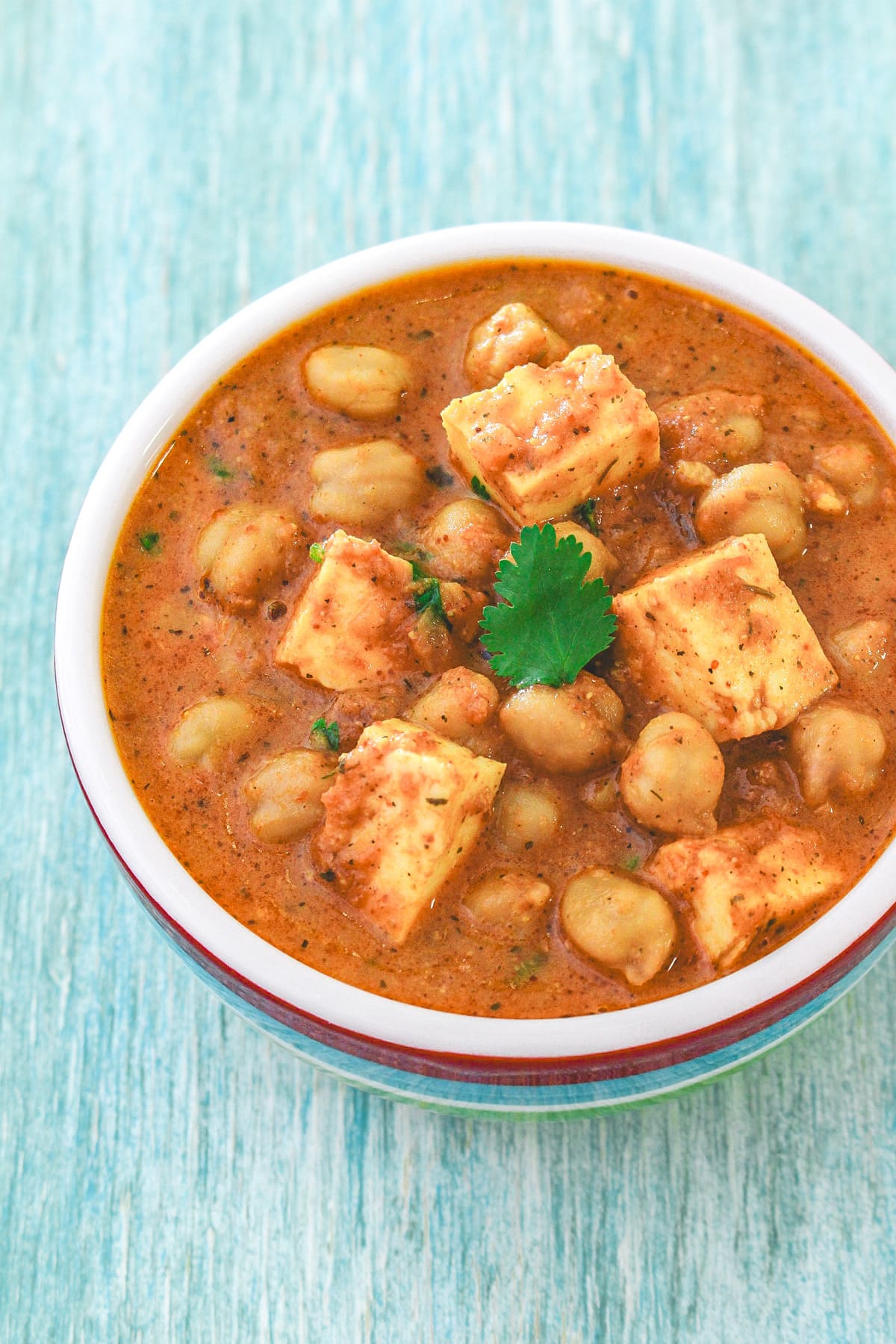 A bowl chole paneer garnished with cilantro.