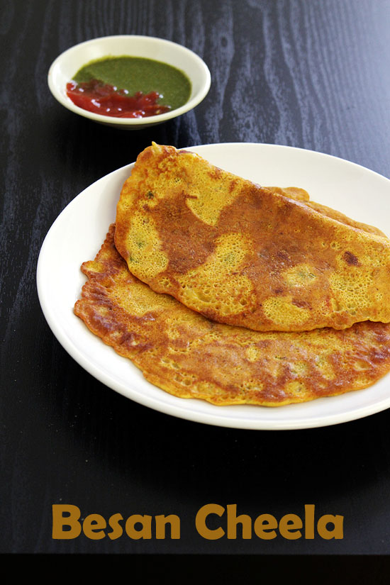 Besan Cheela folded in half and served in a plate with chutney and ketchup.