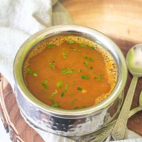 Dal rasam garnished with cilantro with spoons on the side.