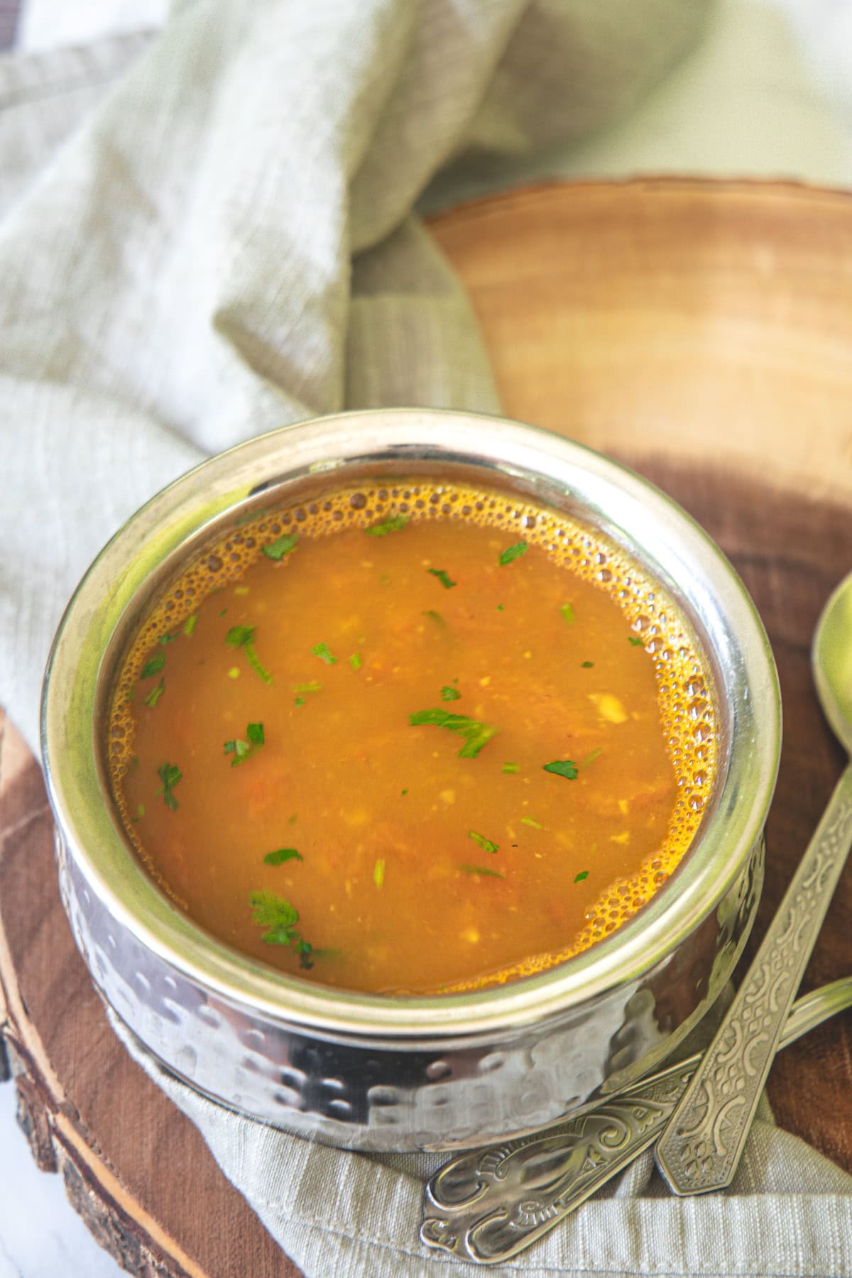 Dal rasam served in a steel serving bowl.
