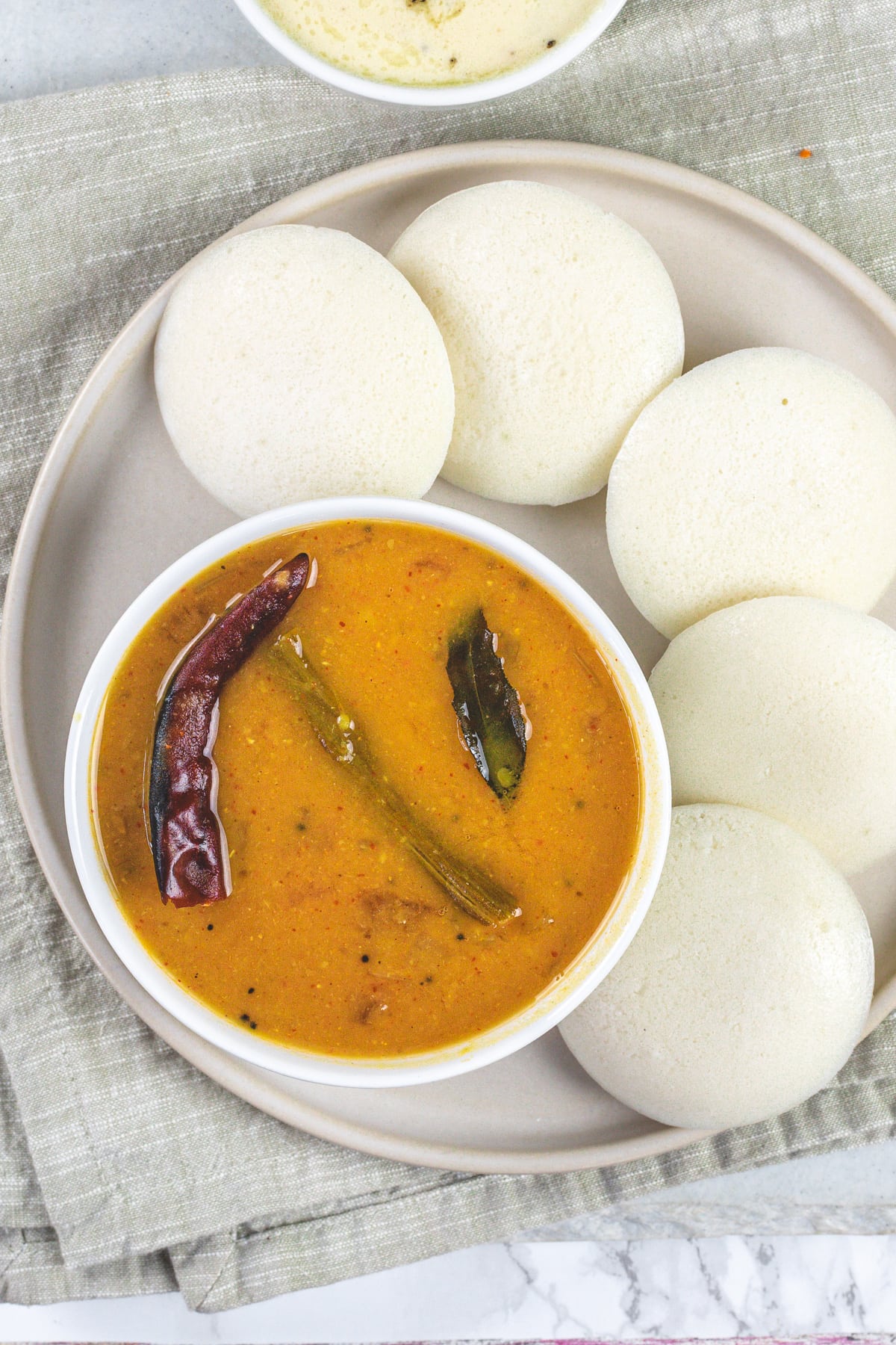 A plate of idli sambar and napkin under it.