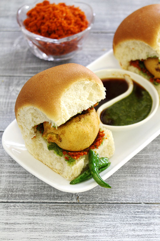 vada pav with fried chili and chutneys.