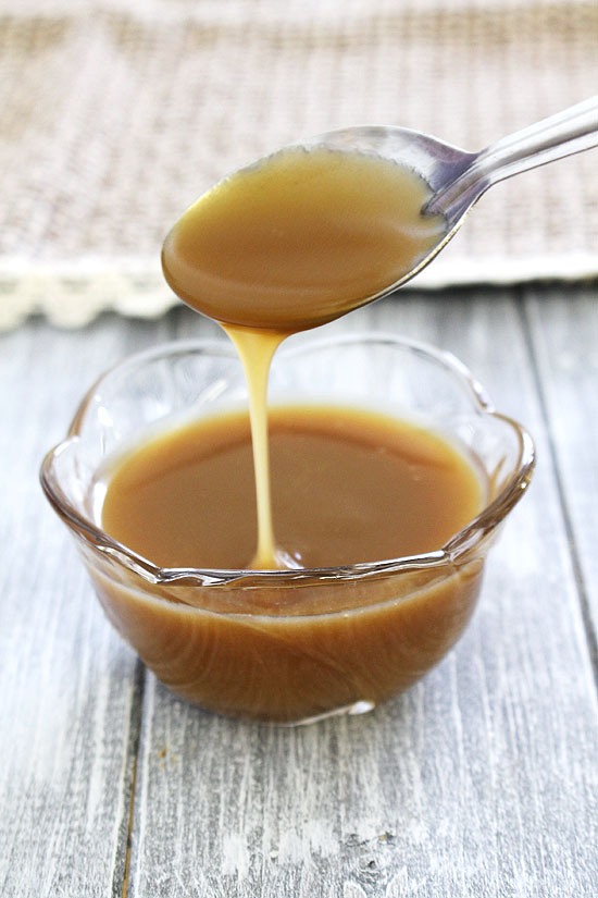 Drizzling butterscotch sauce using a spoon back into the bowl.