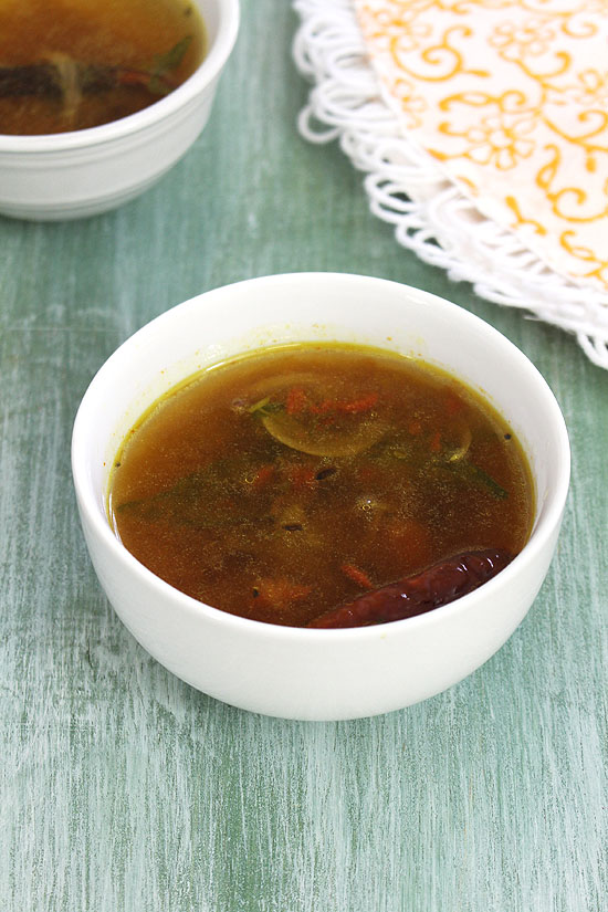 A bowl of rasam with a napkin in the back.