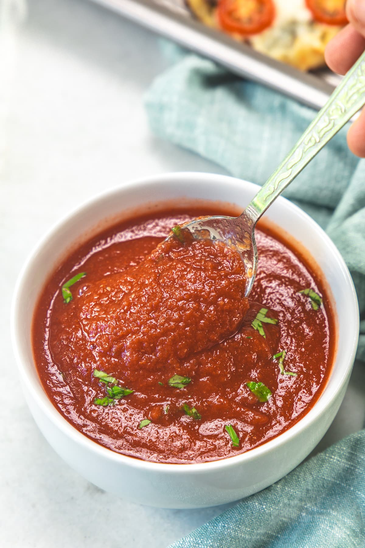 Showing consistency of pizza sauce using a spoon.