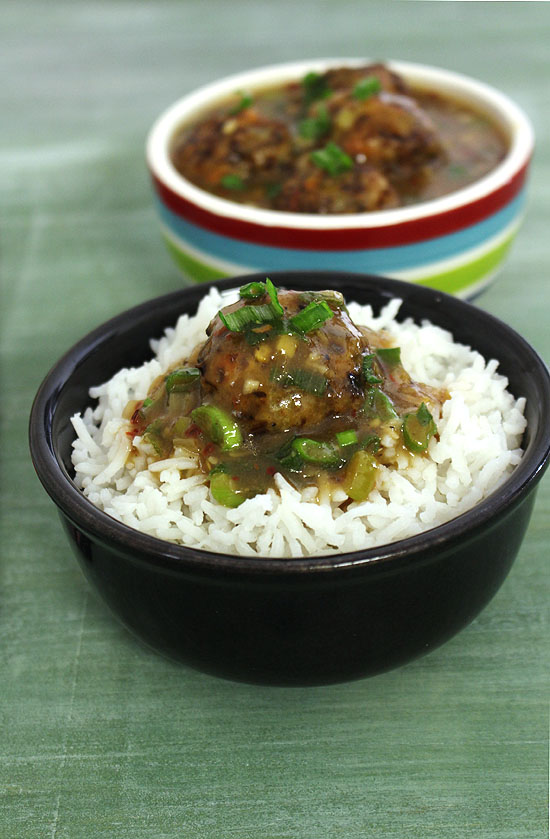 Veg manchurian gravy on a bowl of rice with another bowl of manchurian gravy in the back.