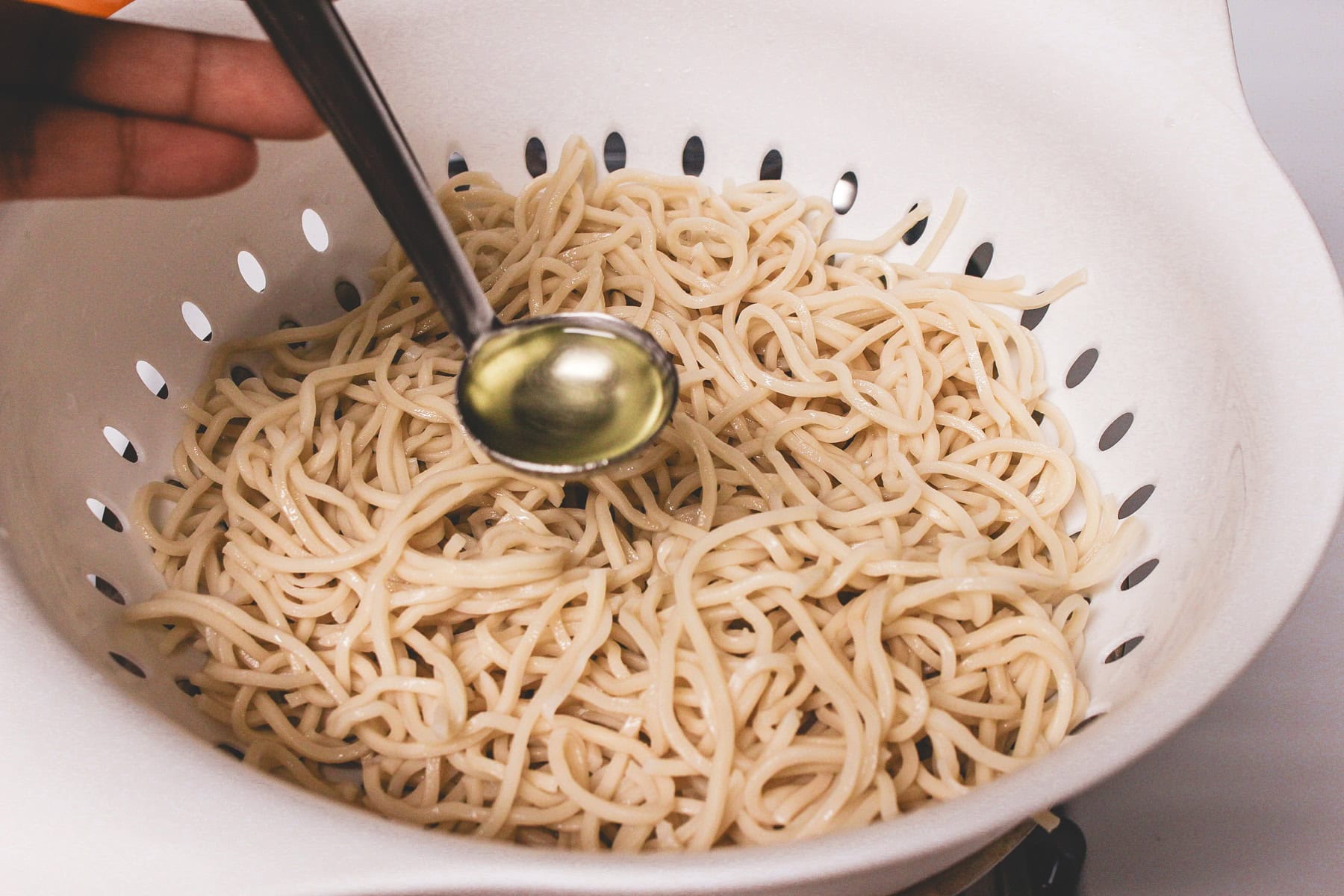 Adding oil in a boiled noodles.