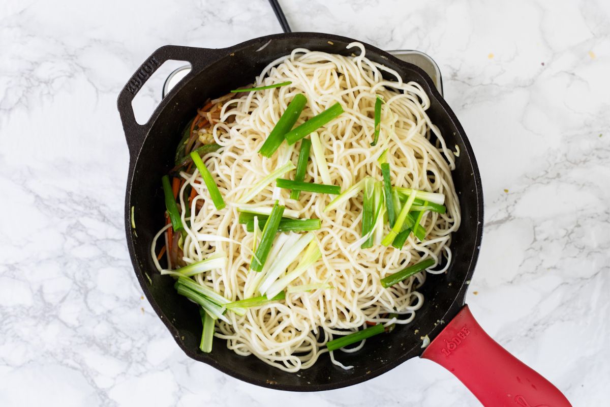 Adding noodles and spring onions in the pan.