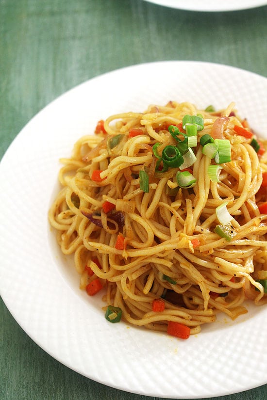 Veg chow mein garnished with spring onion greens.