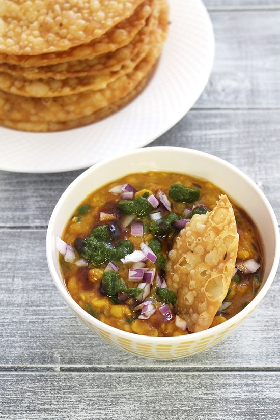 Dal pakwan in a bowl with a stack of pakwan in the back.